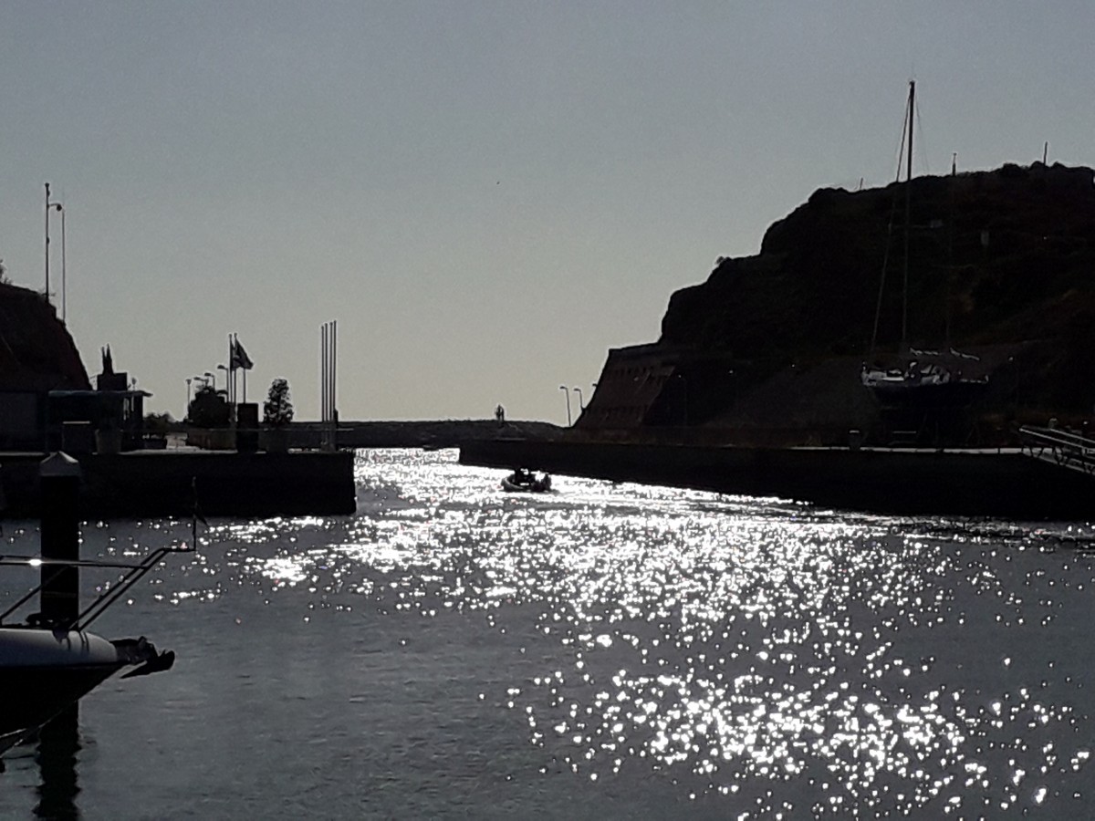 Rubberbootje vaart bij laagstaande zon de haven van de Marina van Albufeira uit. 