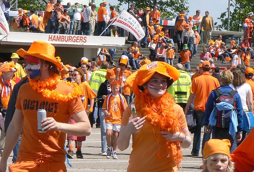 Tientallen mensen in allerlei oranje outfits gekleed.