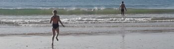 Foto van twee kinderen die op een verlaten strand naar het water rennen