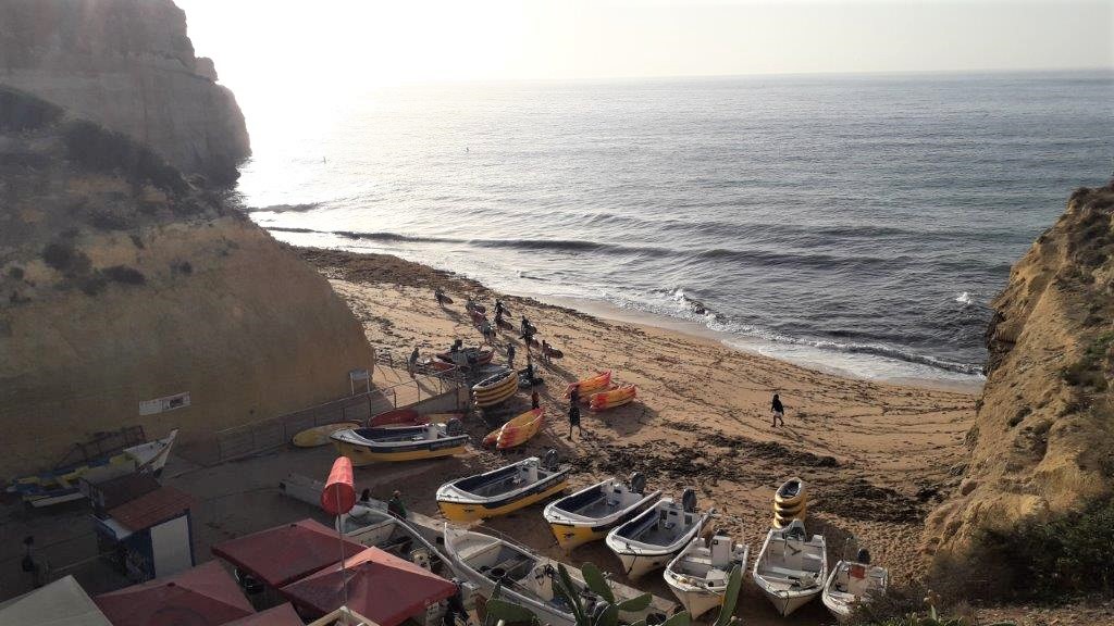 Foto van het strand van Benagil in de Algarve, Portugal, met bootjes en mensen met kano's