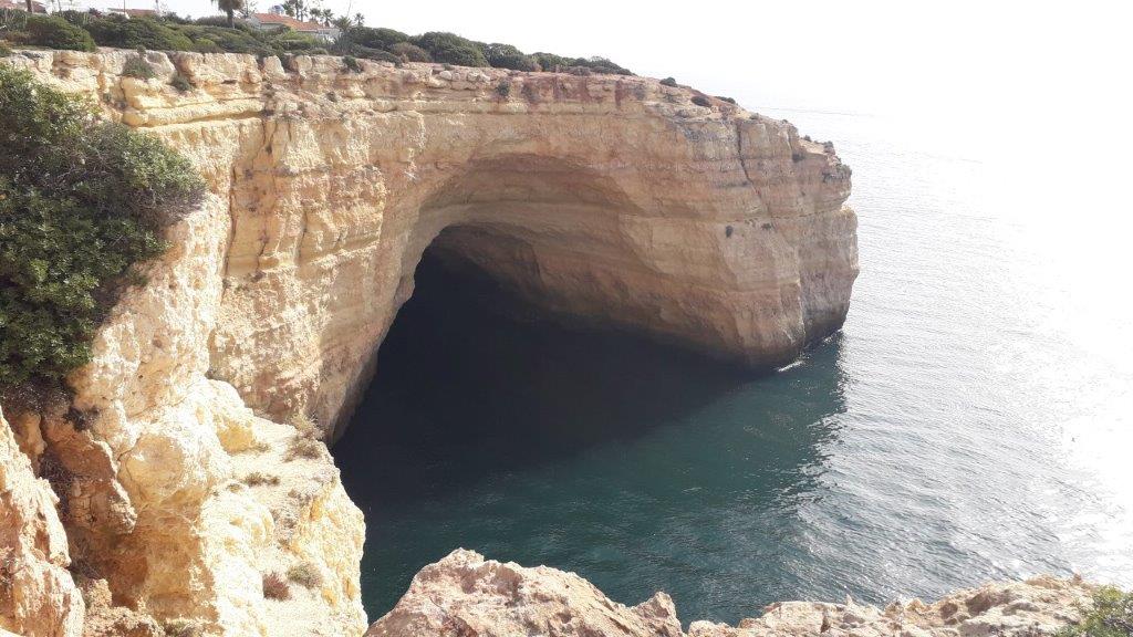 grote rots met enorme inham erin waarboven huizen zijn gebouwd, bij Lagoa in de Algarve in Portugal.