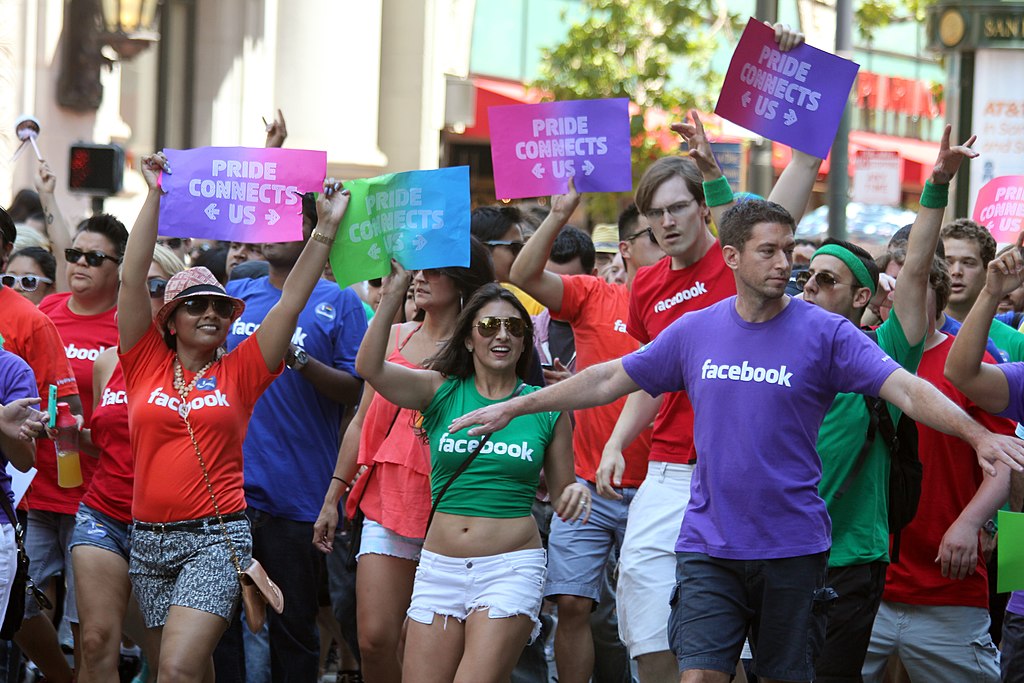 Groep facebook medewerkers die deelneemt aan een Gay pride parade.