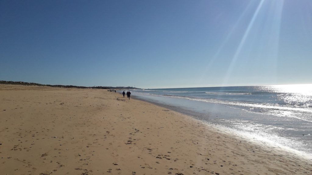 Strandfoto in de Algarve in Portugal met alleen maar blauwe lucht, een zandstrand, en nauwelijks mensen.