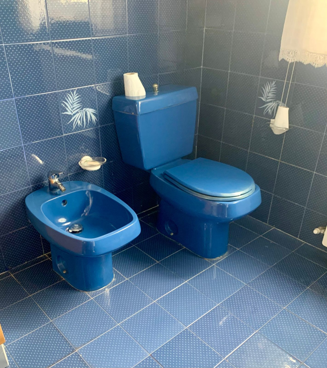 Donkerblauwe set van bidet en toilet in een mooi blauw betegelde badkamer.