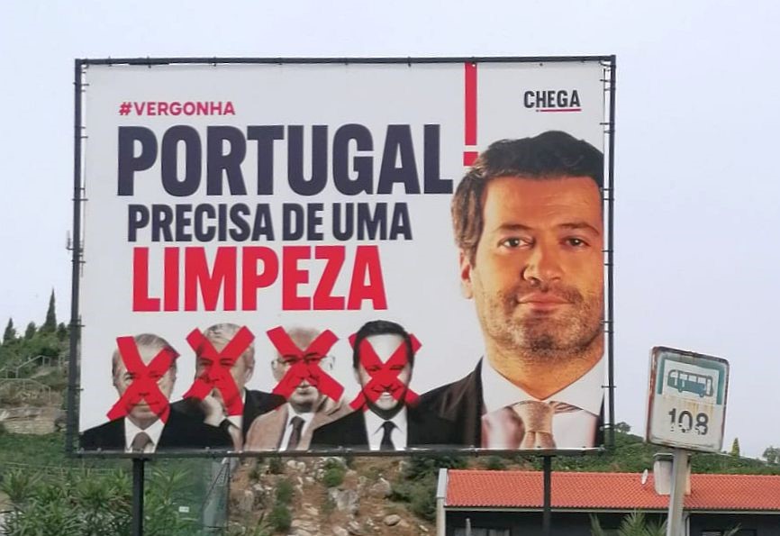 Groot billboard in de openlucht met de verkiezingsleus can Chega 'Portugal precisa de uma limpeza' met ook zichtbaar Antonio Costa, José Socrates en Ricardo Salgado