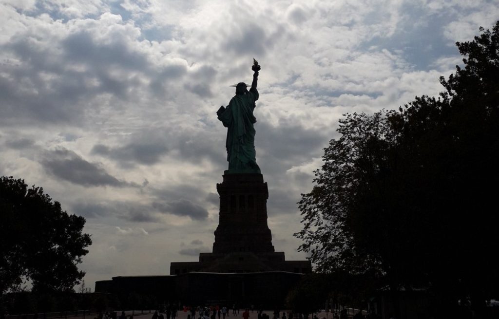 Vrijheidsbeeld in New York van op de rug gezien tegen een bewolkte lucht