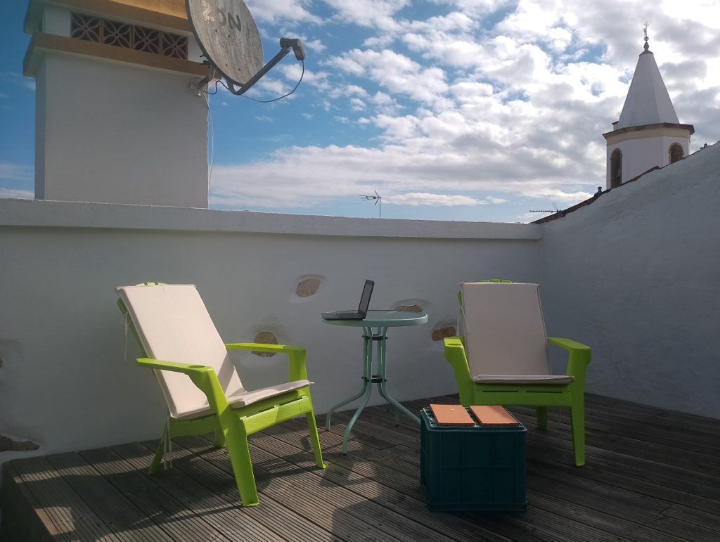 Terrasje op het dak met twee tuinstoelen en een laptop computer.